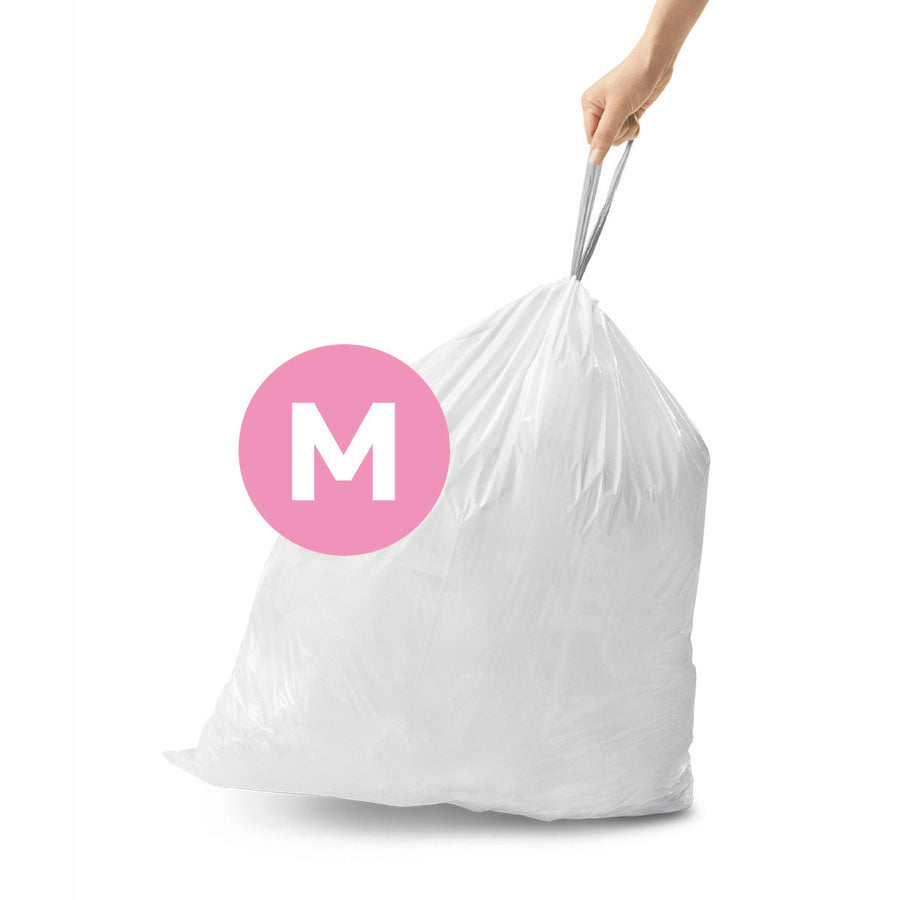 Angled view of Simplehuman Code M white Custom Fit Liner, trash bag lifted by hand using easy-tie drawstrings.
