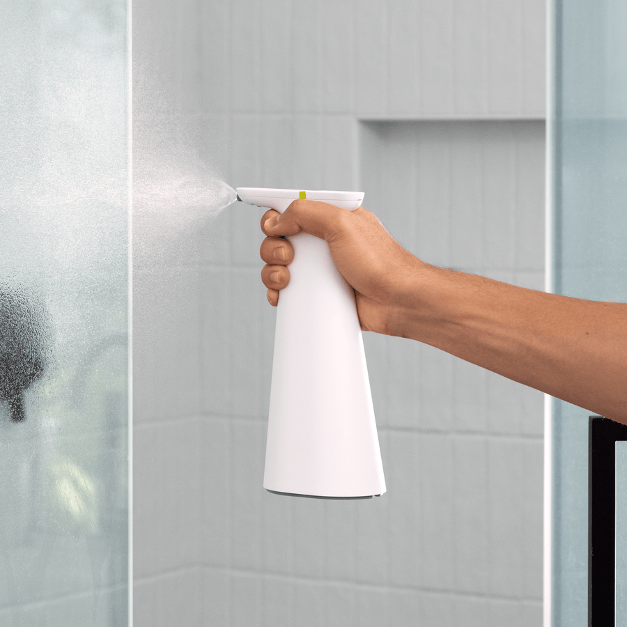 Angled view of Simplehuman White Sensor Spray being used on shower glass, touch-free automatic spray.